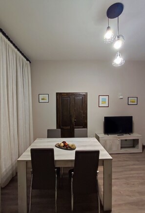 Ein Essbereich mit Tisch, Stühlen, einem Fernseher und einer Deckenleuchte.
