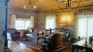 A cozy room with wooden ceilings, a chandelier, stone walls, leather sofas, and a dining table with chairs. - Douro and Tâmega - Quinta do Baroco  (Penafiel)