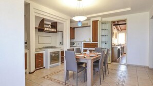 A spacious kitchen with a dining area, featuring a large table and chairs, a microwave, and wooden cabinets.