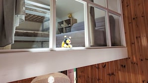 Ein Zimmer mit Fenster und Blick auf eine Treppe sowie einem Bett.