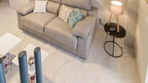 En moderne stue med en sofa, et lille bord og en hængende lampe.