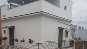 A two-story building with a balcony, a small window, and a door.