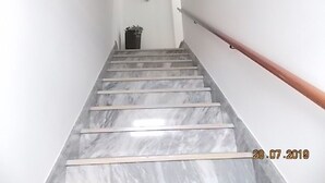 A marble staircase with a wooden handrail leading to a landing.