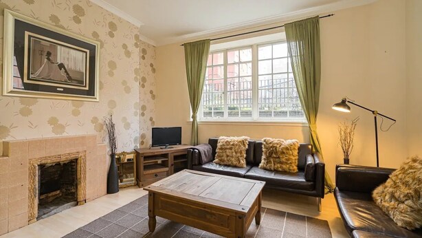 Ein Wohnzimmer mit Kamin, einer Couch, einem Couchtisch und einem Fernseher.