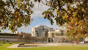 Ein modernes Gebäude mit außergewöhnlichem architektonischen Design, umgeben von einem gepflegten Park mit Teich und Wegen.
