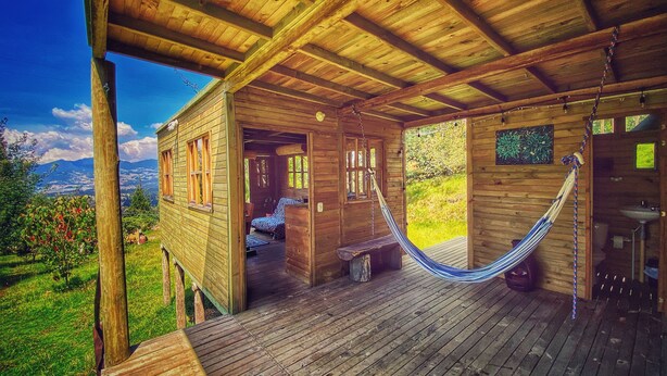 A wooden cabin with a hammock, wooden deck, and a view of the mountains. - Cabaña Agrreste Bed & Breakfast (Nemocón)