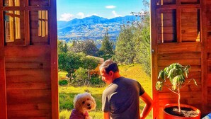 A wooden cabin with a large open door leading to a scenic view of mountains and trees. - Cabaña Agrreste Bed & Breakfast (Nemocón)