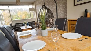 Une table à manger dressée avec des assiettes, des couverts et des verres à vin, entourée de chaises en cuir noir.