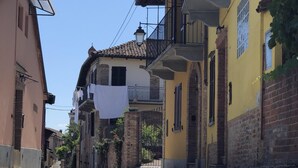 Eine Kopfsteinpflasterstraße mit Gebäuden an beiden Seiten, mit Balkonen und blauem Himmel.