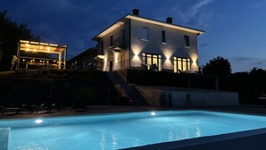 Ein großes Haus mit Schwimmbad, überdachter Terrasse und einer Treppe, die zum Haus führt.
