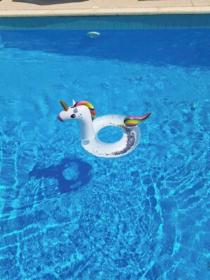 Une piscine d’un bleu éclatant avec un flotteur en forme de licorne.