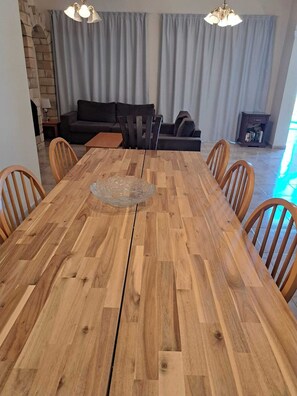 Un coin repas avec une table en bois, six chaises et un lustre.