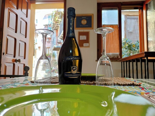 A bottle of wine, two wine glasses, and a green plate on a table with a patterned tablecloth.