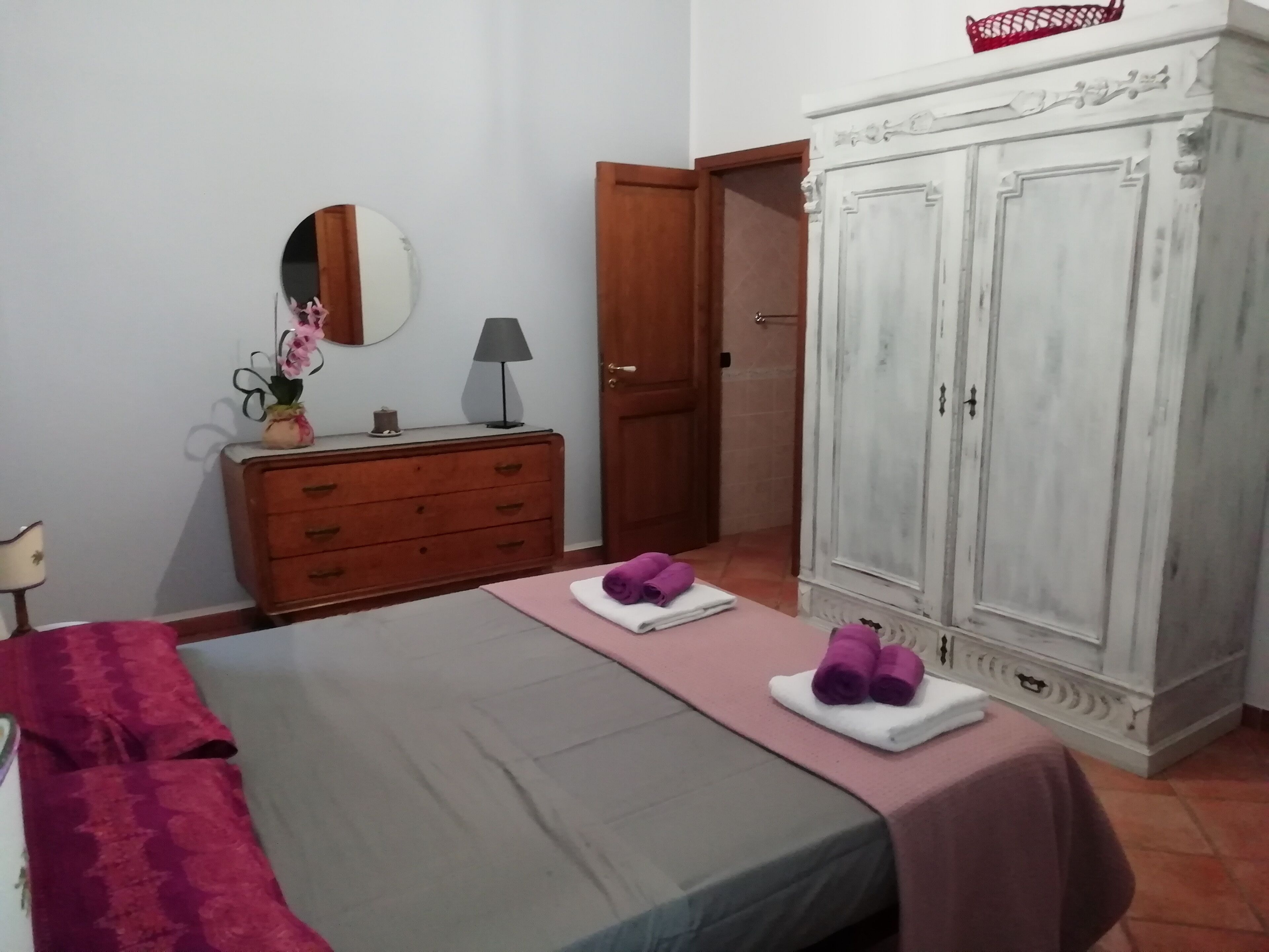 A bedroom with a bed, a dresser, a wardrobe, and a mirror.
