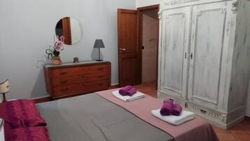 A bedroom with a bed, a dresser, a wardrobe, and a mirror.