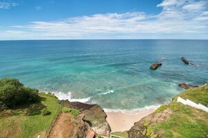 Un paisaje costero con aguas turquesas cristalinas, afloramientos rocosos y una playa arenosa.
