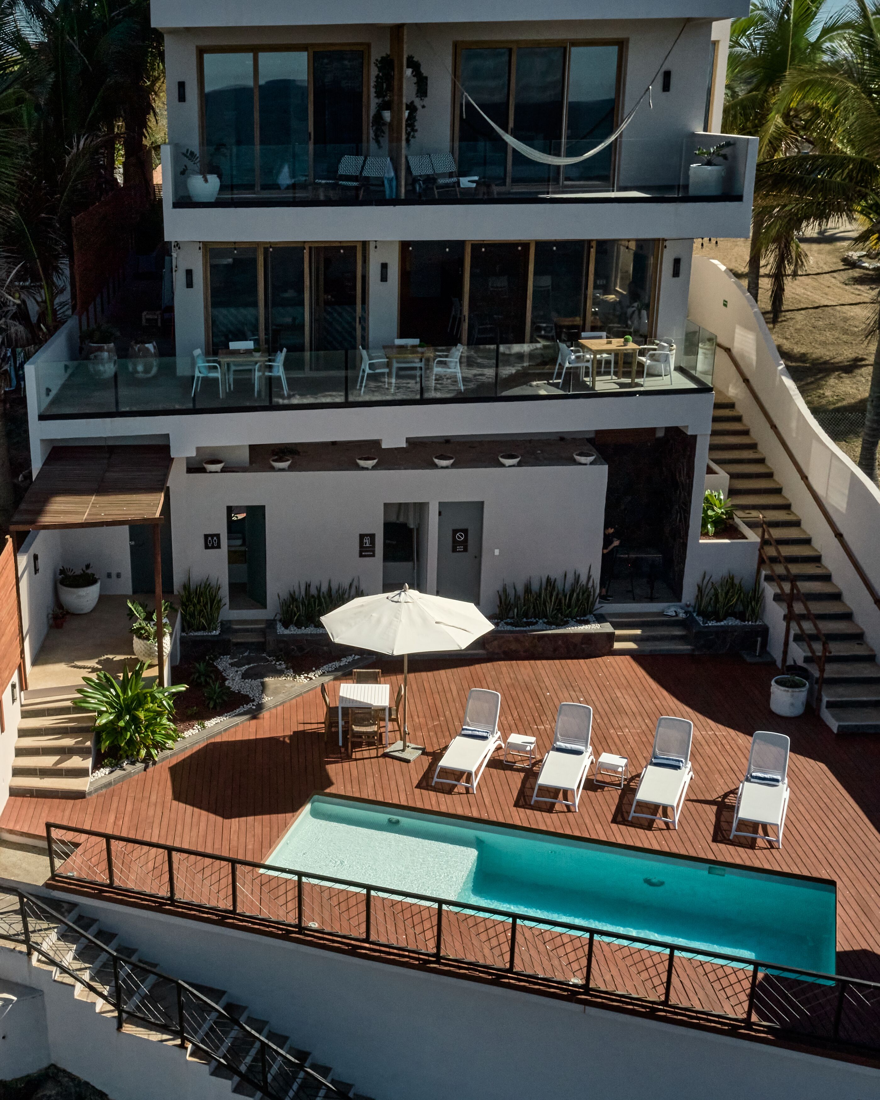 A modern two-story house with a rooftop pool, outdoor seating, and a staircase leading to the upper level.
