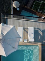 Un área de piscina en la azotea con sillones de descanso y sombrillas.
