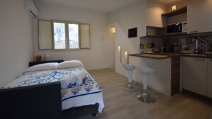 Ein kompaktes Hotelzimmer mit Bett, einer kleinen Küchenzeile und einem Fenster.