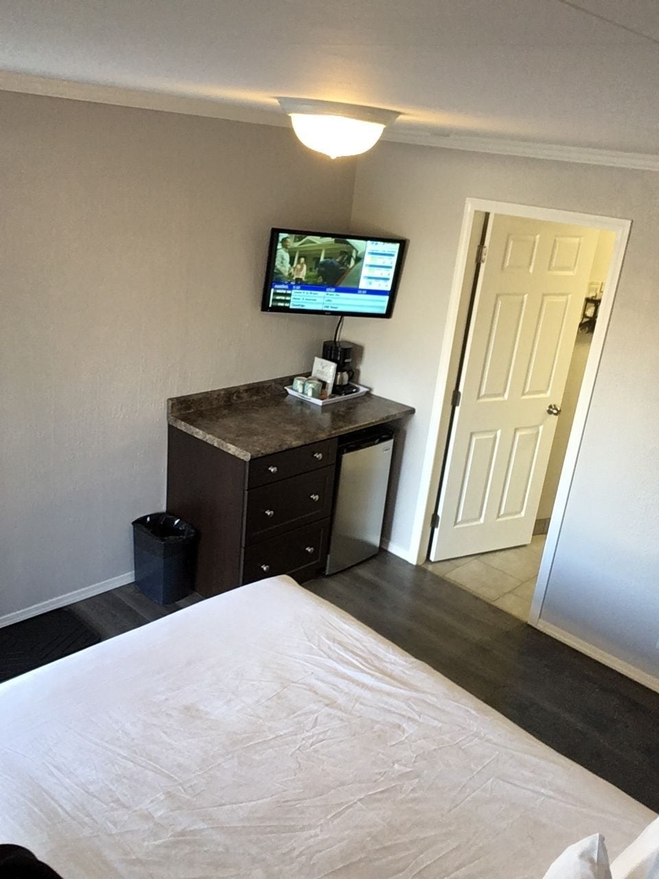 A hotel room with a bed, a desk with a computer, a television, and a door.