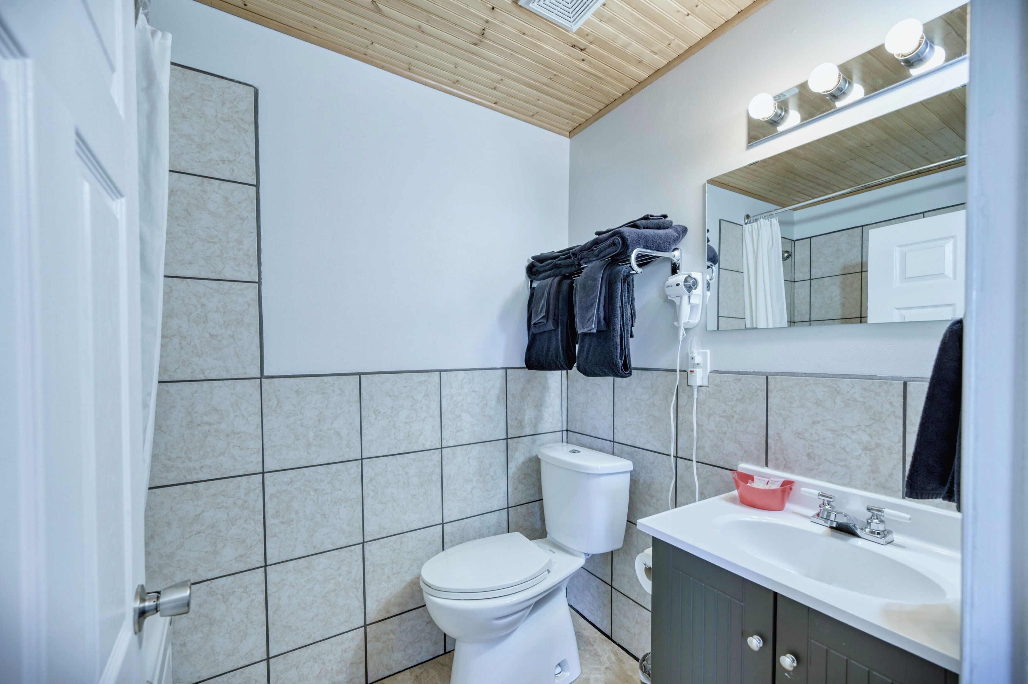 A bathroom with a toilet, sink, mirror, and towel rack.