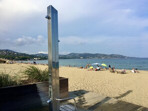A beach with a wooden deck and a metal structure, possibly a lifeguard tower, overlooking the sea.