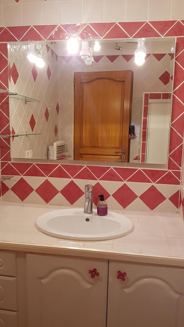 A bathroom with a white sink, a mirror above it, and a wooden cabinet below. - Welcome "Chez Romane" Aiguèze (Aiguèze)