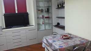 A compact kitchen with a built-in oven, a glass cabinet, and a dining table with a quilted tablecloth. - SMITHS & HERREROS (Codie CIN IT010025C2Q2M67QJW) (Genova)