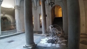 Un vaste hall orné de grandes colonnes, d’une sculpture en spirale et d’un escalier menant à un niveau supérieur.