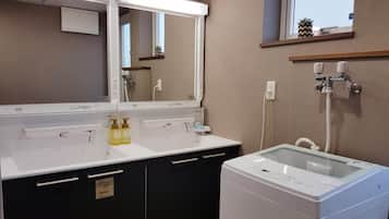 A modern bathroom with a large mirror, a hair dryer, and a washing machine.
