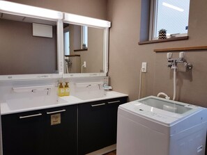 A modern bathroom with a large mirror, a hair dryer, and a washing machine.