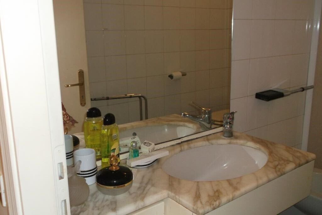 A bathroom with a marble sink, a mirror, and toiletries.