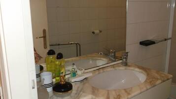A bathroom with a marble sink, a mirror, and toiletries.