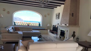 A modern living room with a large window, a fireplace, and a sofa set. - Secluded, Spacious, Luxury Villa & Swimming Pool in Beautiful Rustic Location  (Benidoleig)