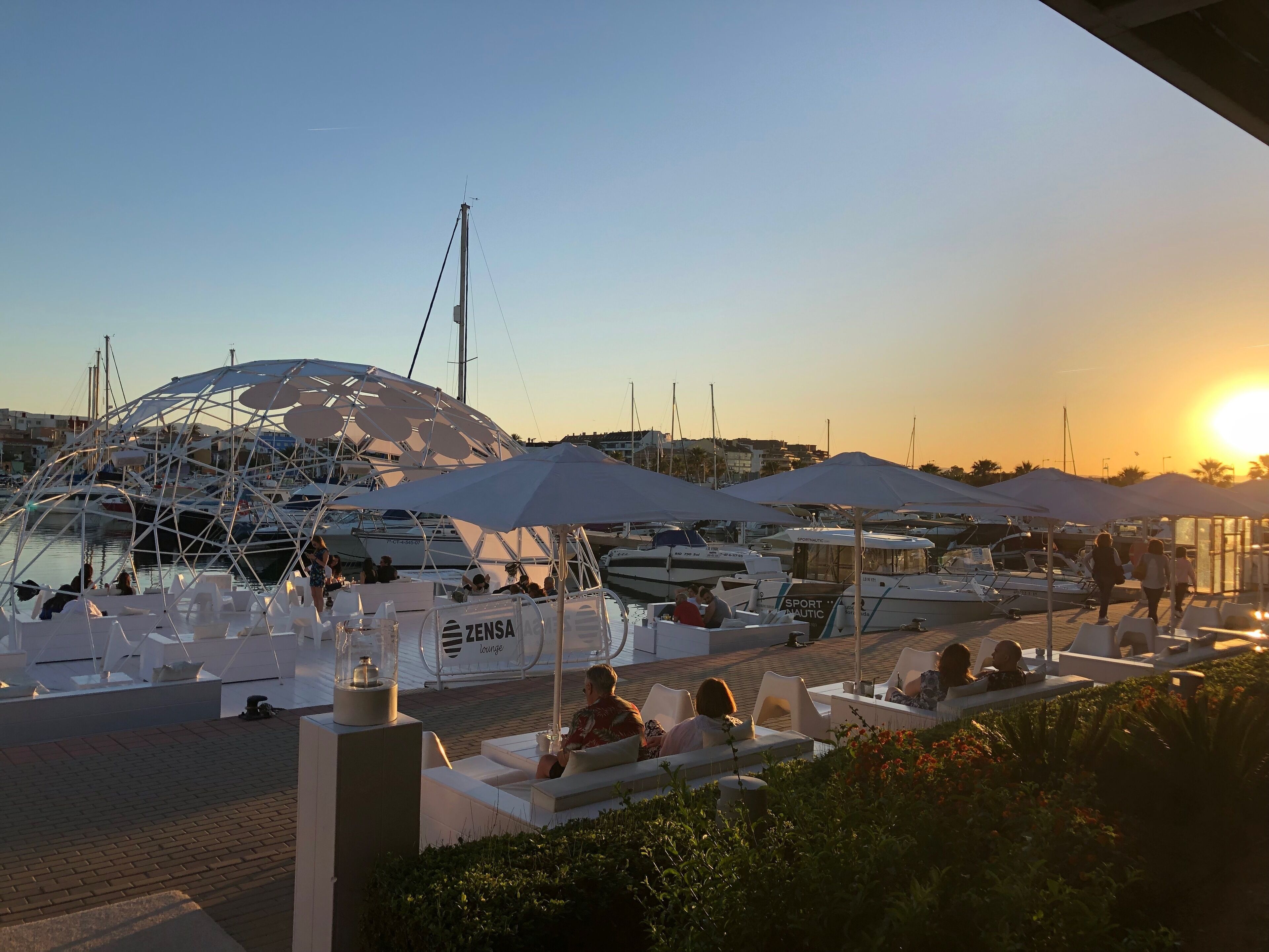 A marina with boats, lounge seating, and umbrellas.