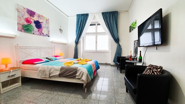 Een hotelkamer met een bed, bureau, stoel, televisie en een raam met gordijnen.