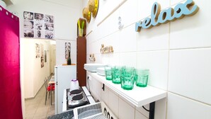 Een keuken met een wit aanrecht, groene glazen en een bordje met de tekst 'relax' aan de muur.