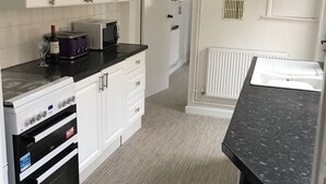 A modern kitchen with white cabinets, a black countertop, and a built-in oven. - Cosy & Comfortable Entire Holiday Home, Llanelli. Fully equipped. Dog friendly (Llanelli)