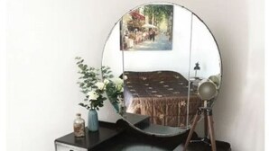 A dark wooden vanity with a round mirror, a small stool, and a vase with flowers. - Cosy & Comfortable Entire Holiday Home, Llanelli. Fully equipped. Dog friendly (Llanelli)