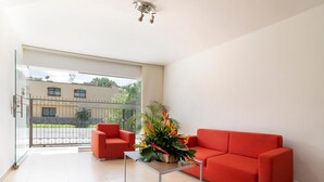 Un salon moderne avec un canapé rouge, une petite table et une plante en pot.