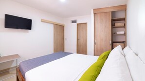 Une chambre à coucher avec un lit, un téléviseur fixé au mur et des armoires en bois.