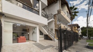 Un immeuble à plusieurs étages avec une façade vitrée, un escalier et une entrée fermée par un portail.