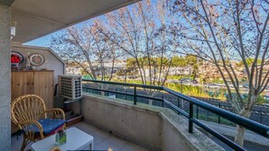 En balkon med et bord, stole, et træskab og en klimaanlæg.