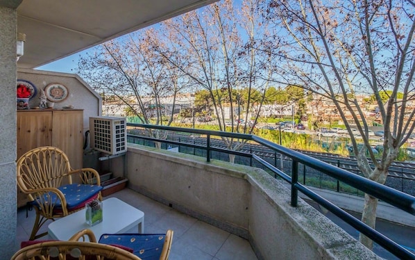 A balcony with a table and chairs, a wooden cabinet, and an air conditioning unit.