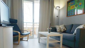En moderne stue med sofa, sofabord, fjernsyn og en balkon med stol.
