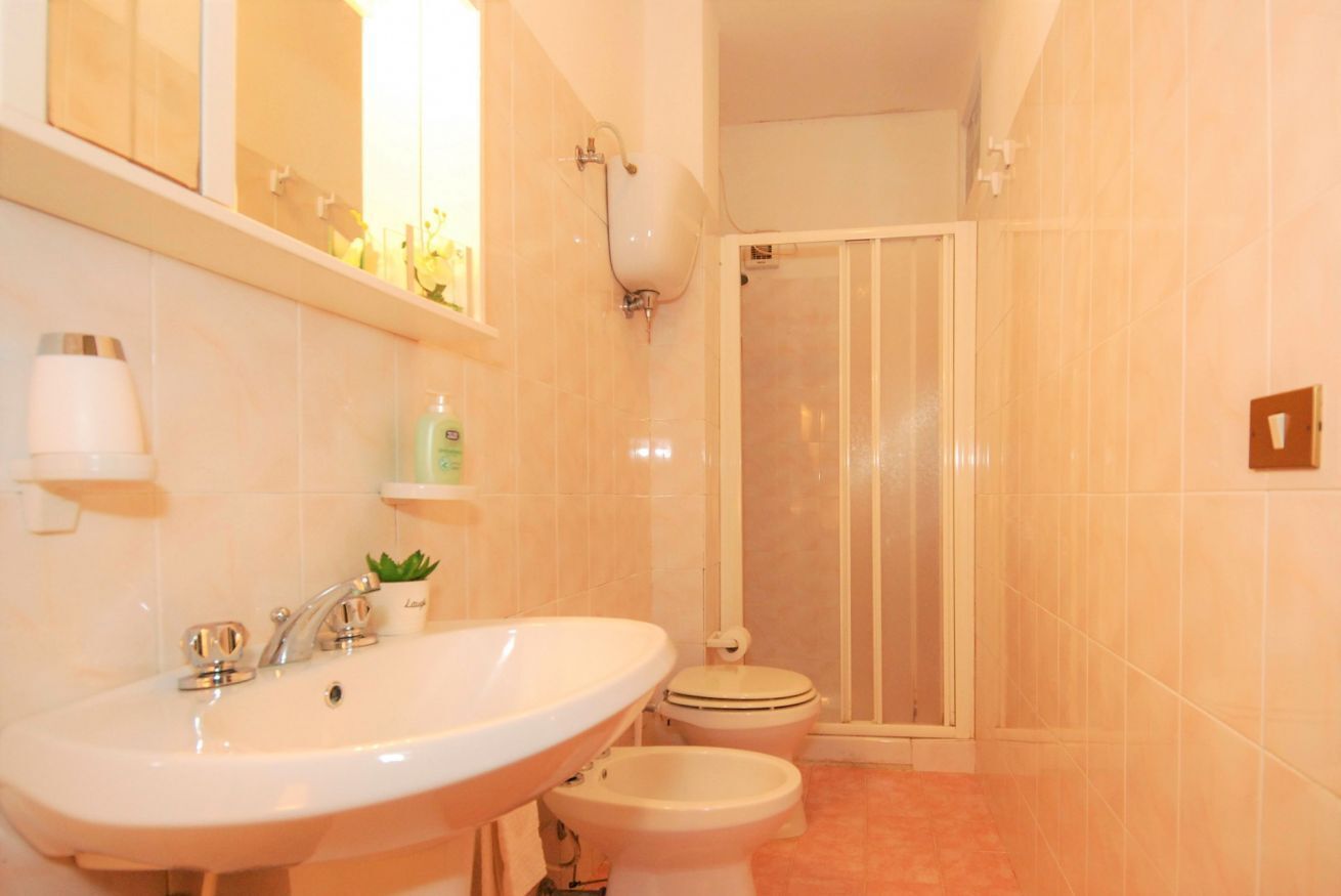 A bathroom with a sink, bidet, toilet, and shower.