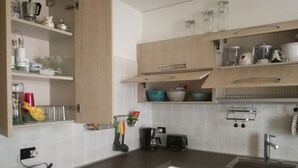 A modern kitchen with wooden cabinets, a built-in sink, and various kitchen appliances. - Mount N Lake Apartment -Ledro Garda (Ledro)