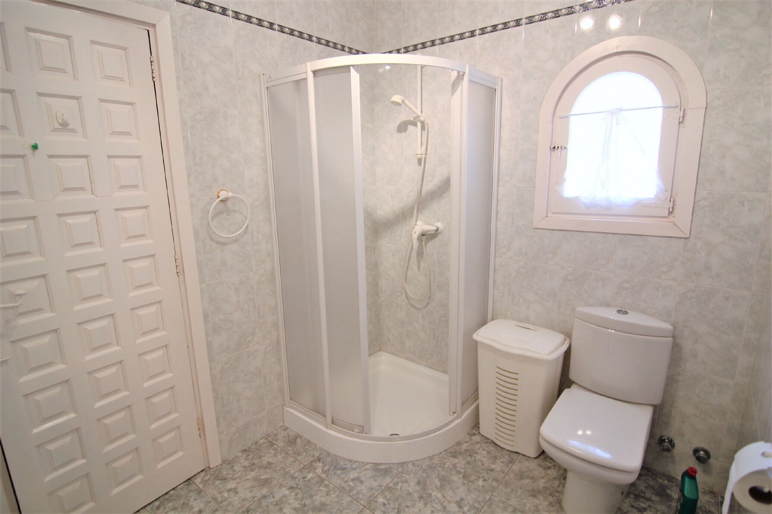 Ein Badezimmer mit Duschkabine, Toilette und Tür.