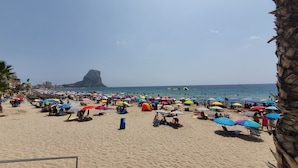 A crowded beach with numerous colorful umbrellas and people enjoying the sun.