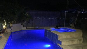 En pool med blått ljus, en konstgjord vattenfallskaskad och en kant av sten.
